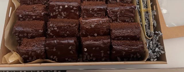 A large flat box packed with squares of chocolate chip brownies.